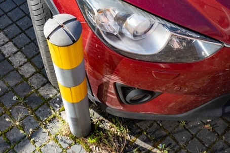 Red car scratched when parking near yellow pole
